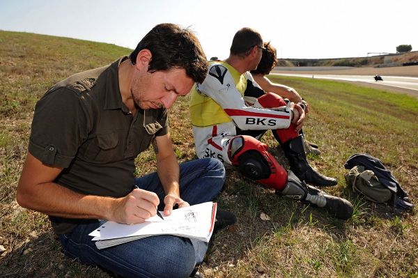 Jenfèvre en train de dessiner à côté de Pat Perna, le scénariste, que Moto Journal avait invité à un stage de pilotage "pour l'inspiration".